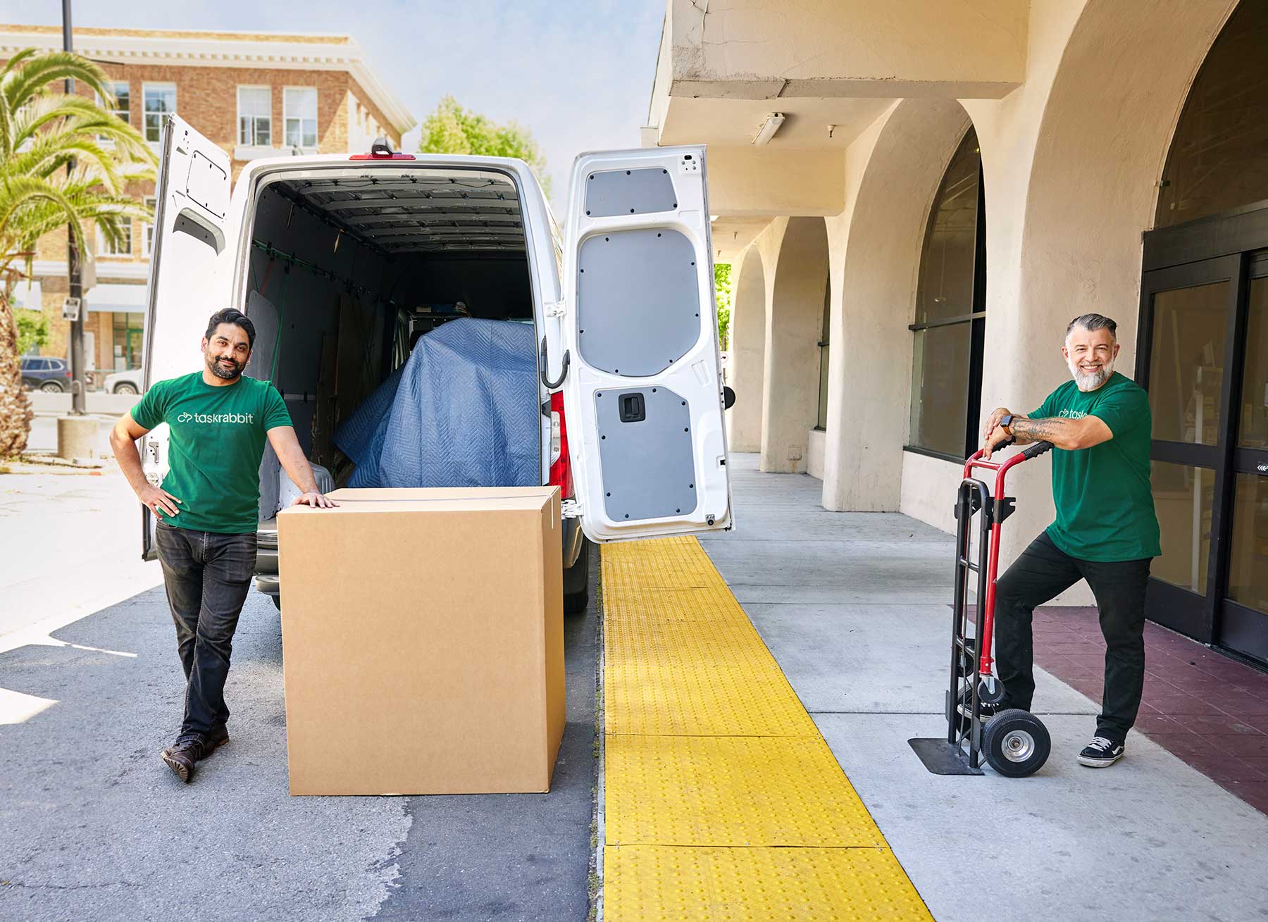 2 Dolly Helpers moving a box outside of a store
